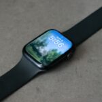 Fitness‑Tracker und Smartwatch liegen nebeneinander auf einem Laufband.