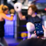 Vier Fitness-Tracker mit ihren Smartphone-Apps, die verschiedene Regenerationsmetriken wie Schlafphasen, Herzratenvariabilität (HRV) und Erholungswerte anzeigen.