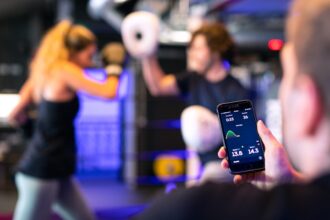 Vier Fitness-Tracker mit ihren Smartphone-Apps, die verschiedene Regenerationsmetriken wie Schlafphasen, Herzratenvariabilität (HRV) und Erholungswerte anzeigen.