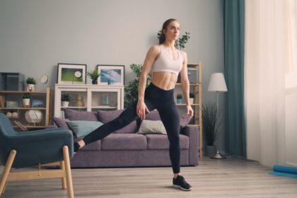 Close-up eines verstellbaren Hometrainer-Fußes mit Fitness-Tracker am Handgelenk im Hintergrund.