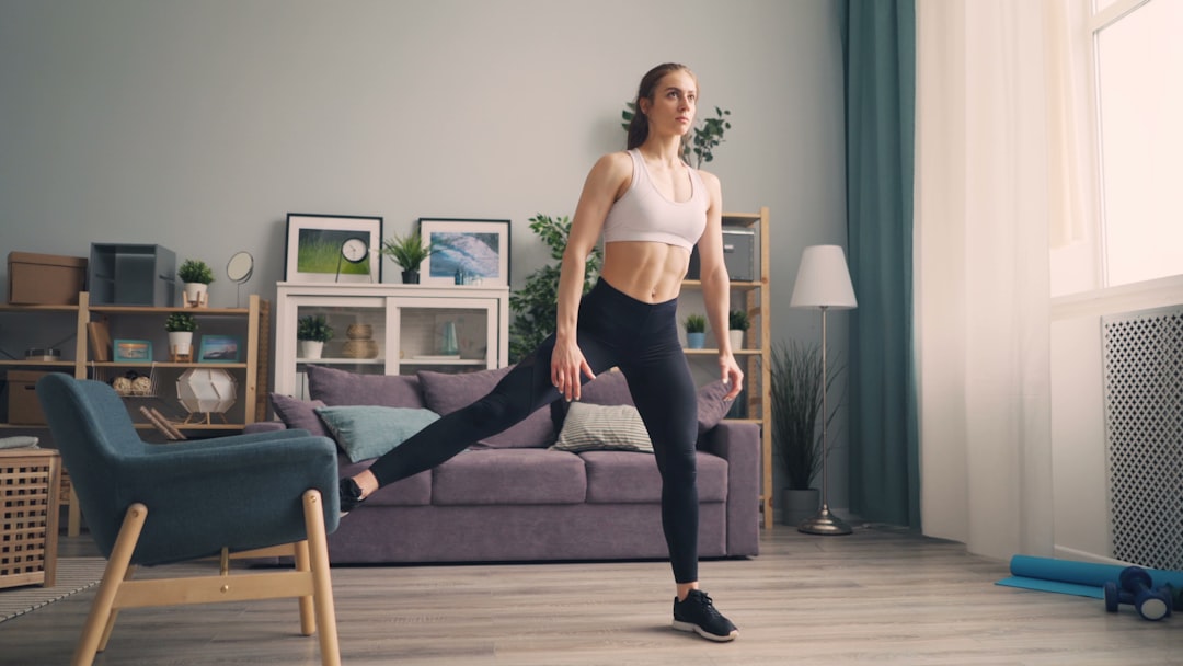 Close-up eines verstellbaren Hometrainer-Fußes mit Fitness-Tracker am Handgelenk im Hintergrund.