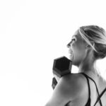 Verstellbare Hanteln in verschiedenen Gewichtsstufen auf einem Fitnessmatte, daneben ein Smartphone mit geöffneter Fitness-Tracker-App.