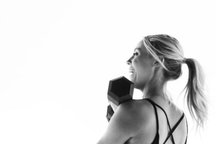 Verstellbare Hanteln in verschiedenen Gewichtsstufen auf einem Fitnessmatte, daneben ein Smartphone mit geöffneter Fitness-Tracker-App.